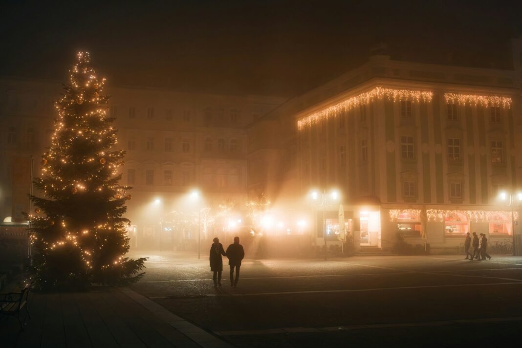 Couple walking past christmas tree in foggy city